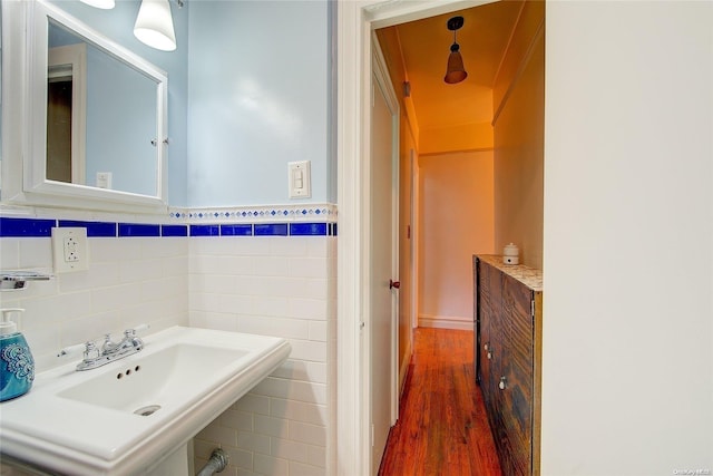 bathroom with hardwood / wood-style flooring, sink, and tile walls