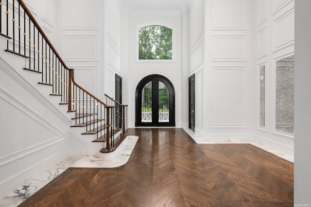 foyer with ornamental molding, a high ceiling, and french doors