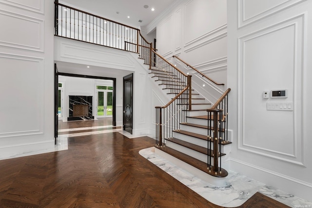 foyer with crown molding, a towering ceiling, and parquet floors