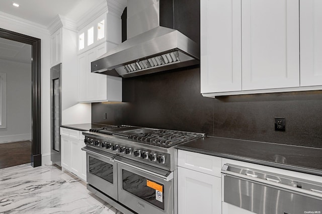 kitchen with stainless steel appliances, white cabinetry, and wall chimney exhaust hood