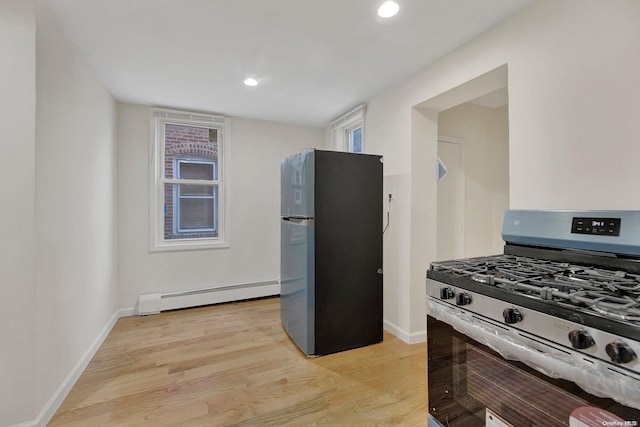 kitchen with light wood-type flooring, appliances with stainless steel finishes, and a baseboard radiator