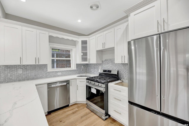 kitchen featuring light hardwood / wood-style floors, light stone countertops, white cabinetry, and stainless steel appliances