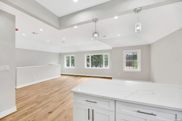 kitchen featuring white cabinetry, light hardwood / wood-style flooring, hanging light fixtures, and light stone counters