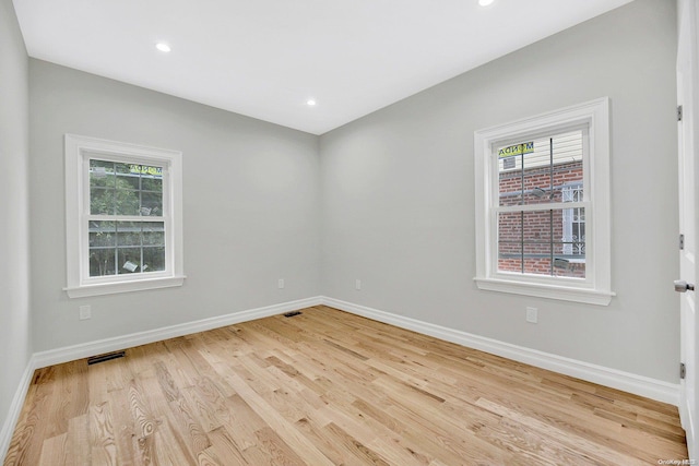 unfurnished room with a healthy amount of sunlight and light hardwood / wood-style floors