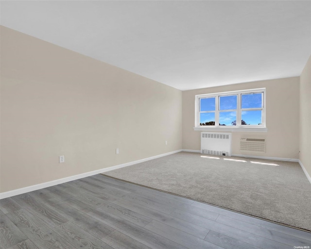 spare room with radiator heating unit and light hardwood / wood-style flooring