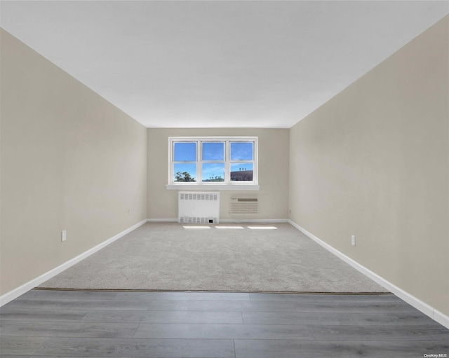 unfurnished living room featuring wood-type flooring and radiator