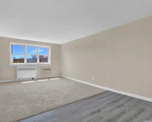 empty room featuring light hardwood / wood-style floors, radiator heating unit, and an AC wall unit