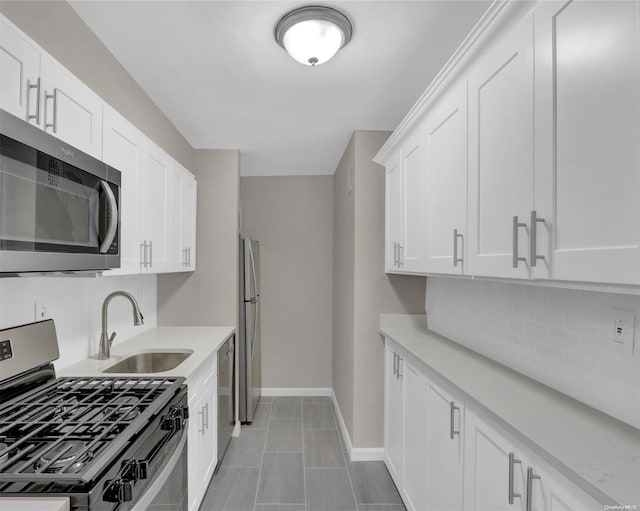 kitchen with white cabinets, sink, light stone countertops, light tile patterned flooring, and stainless steel appliances