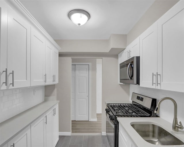 kitchen with sink, stainless steel appliances, light hardwood / wood-style flooring, decorative backsplash, and white cabinets