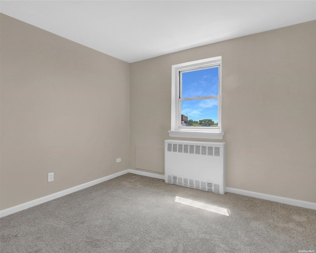 unfurnished room with radiator heating unit and carpet floors