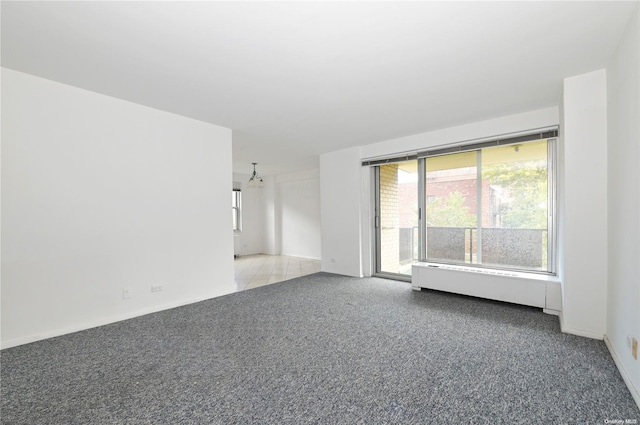 empty room featuring baseboard heating and light colored carpet