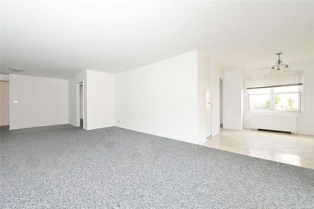 unfurnished room featuring light tile patterned floors, radiator, and a chandelier