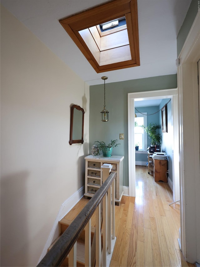 corridor with a skylight and light hardwood / wood-style floors