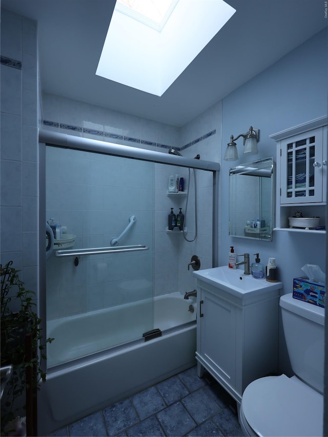 full bathroom with a skylight, vanity, bath / shower combo with glass door, and toilet