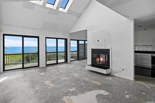 unfurnished living room with a water view, high vaulted ceiling, and a skylight