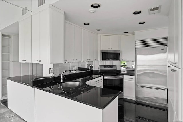 kitchen with kitchen peninsula, stainless steel appliances, white cabinetry, and sink