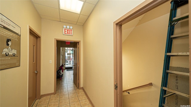 hallway with a drop ceiling and light tile patterned flooring