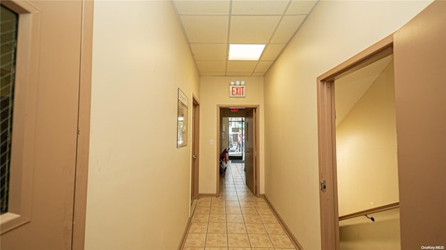 hallway featuring a paneled ceiling and light tile patterned floors