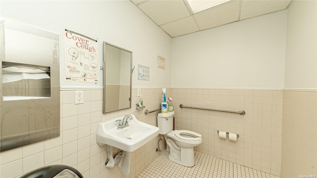 bathroom featuring tile patterned flooring, a drop ceiling, toilet, and tile walls