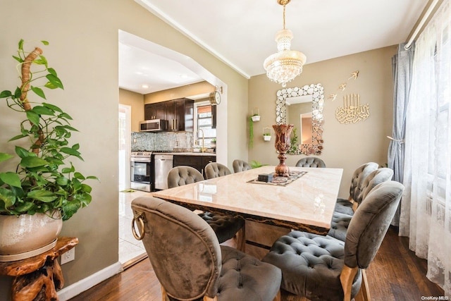 dining room featuring crown molding, dark hardwood / wood-style flooring, sink, and an inviting chandelier