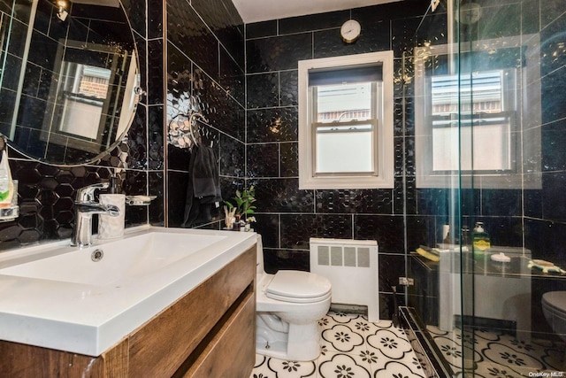 bathroom featuring tile patterned floors, radiator, tile walls, and toilet