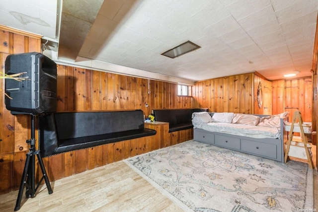 bedroom with light hardwood / wood-style floors and wooden walls