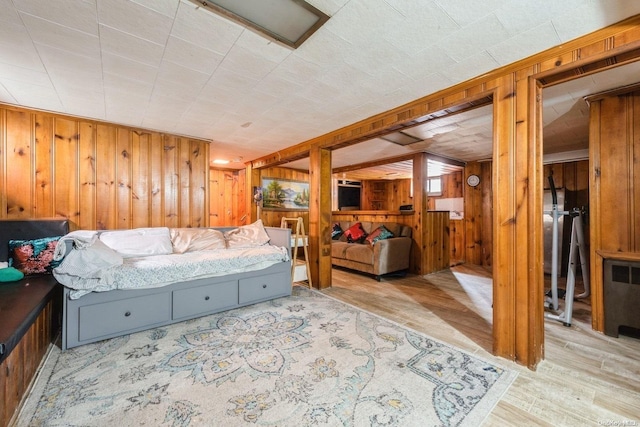 bedroom with radiator, wooden walls, and light wood-type flooring