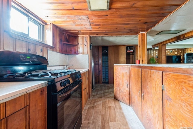 kitchen featuring black gas stove, light wood-type flooring, and wooden ceiling