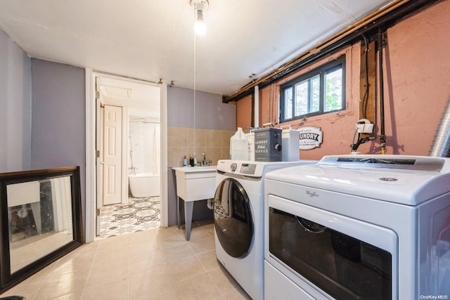 laundry room with cabinets, light tile patterned floors, tile walls, and washing machine and clothes dryer