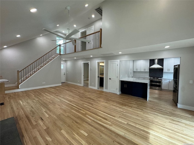 unfurnished living room featuring light wood-type flooring and a high ceiling