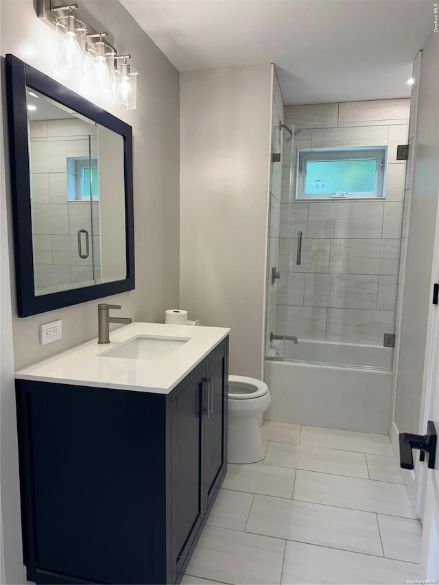 full bathroom with tile patterned floors, vanity, toilet, and bath / shower combo with glass door