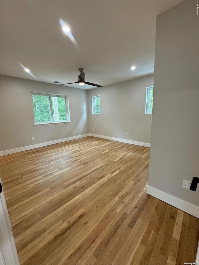 empty room with ceiling fan and light hardwood / wood-style flooring