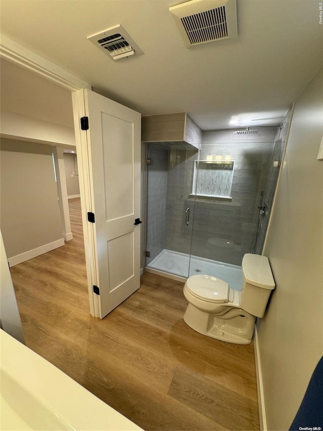 bathroom featuring hardwood / wood-style floors, toilet, and a shower with shower door