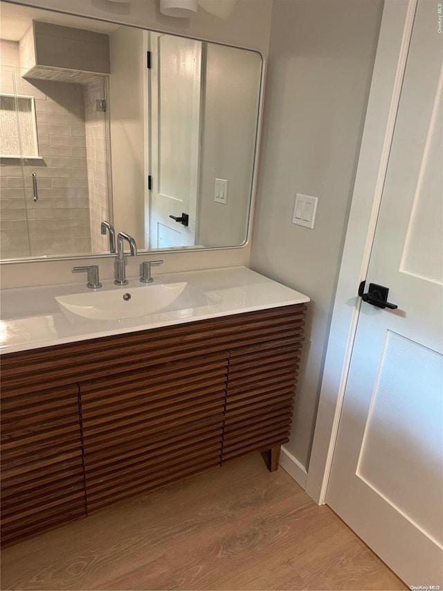 bathroom with hardwood / wood-style floors, vanity, and walk in shower