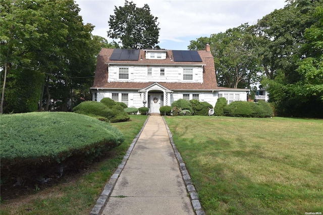 view of front of property featuring solar panels and a front lawn