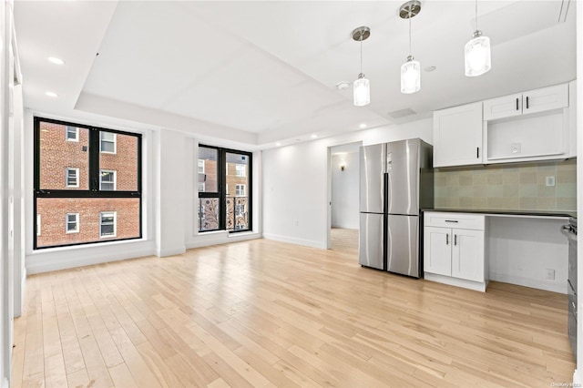 kitchen with stainless steel refrigerator, hanging light fixtures, backsplash, light hardwood / wood-style floors, and white cabinets