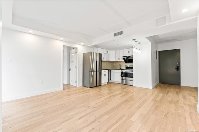 kitchen with white cabinets, decorative backsplash, decorative light fixtures, light hardwood / wood-style floors, and stainless steel appliances