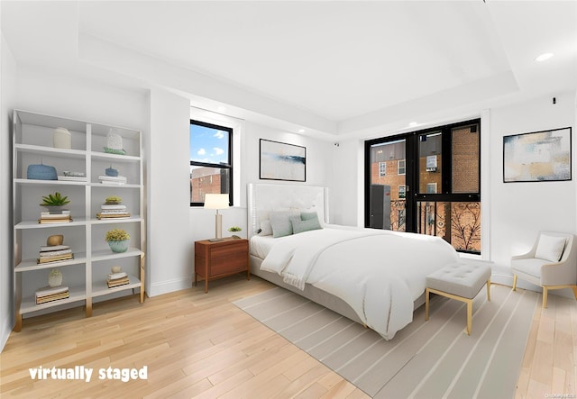 bedroom featuring light hardwood / wood-style floors and a tray ceiling