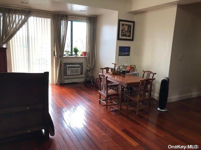 dining area with a wall mounted air conditioner and dark wood-type flooring