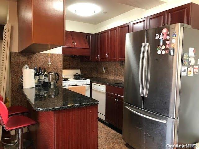 kitchen with premium range hood, tasteful backsplash, a breakfast bar, and white appliances