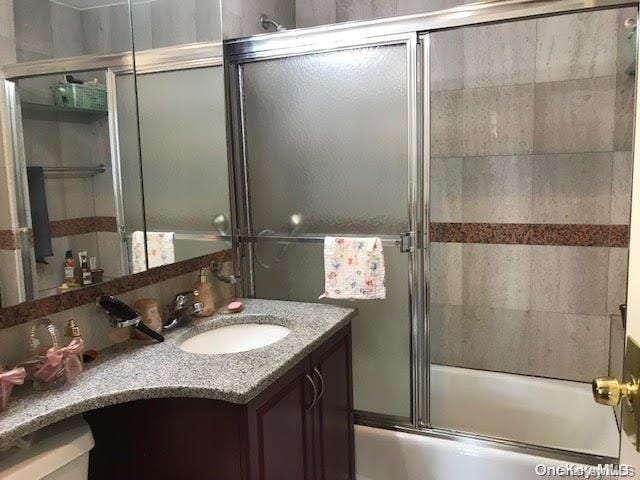 bathroom with vanity and enclosed tub / shower combo