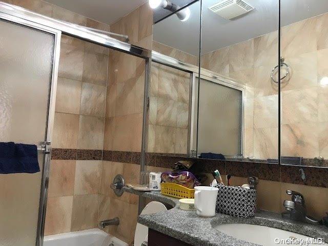 full bathroom featuring vanity, toilet, and enclosed tub / shower combo