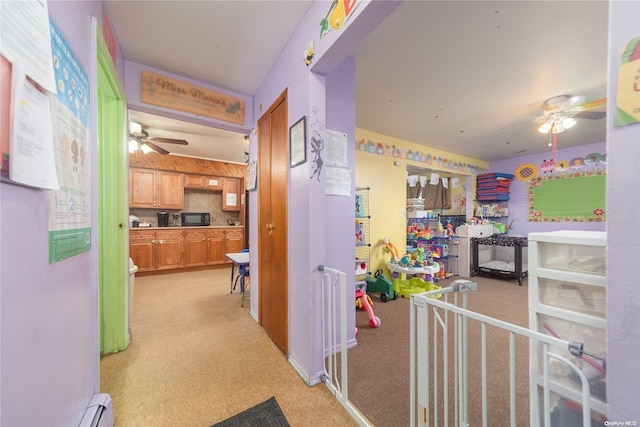 corridor with light carpet and a baseboard heating unit