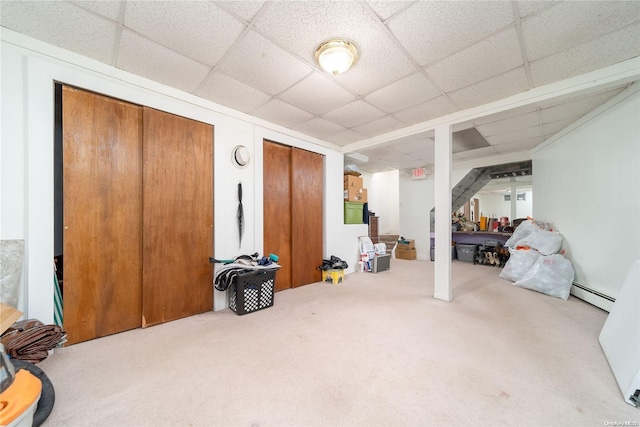 basement with baseboard heating, a paneled ceiling, and carpet floors