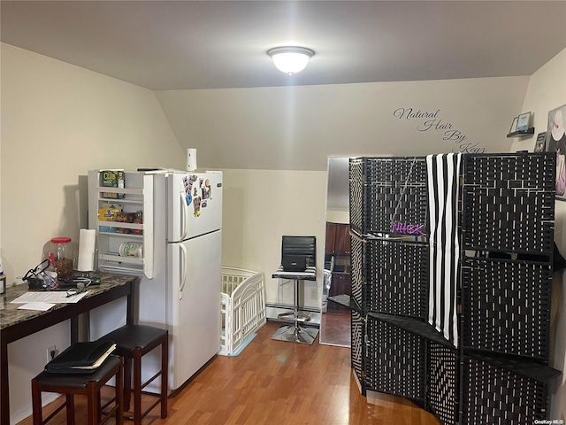 kitchen featuring vaulted ceiling, white refrigerator, and light hardwood / wood-style flooring