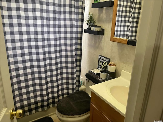 bathroom with vanity, toilet, and tile walls