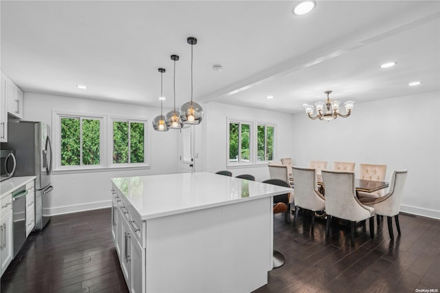 kitchen with white cabinets, a kitchen island, hanging light fixtures, and stainless steel appliances