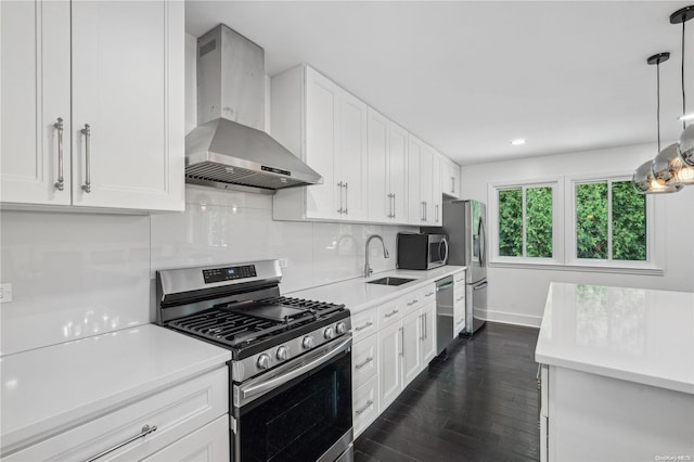 kitchen with white cabinetry, sink, wall chimney exhaust hood, dark hardwood / wood-style flooring, and appliances with stainless steel finishes