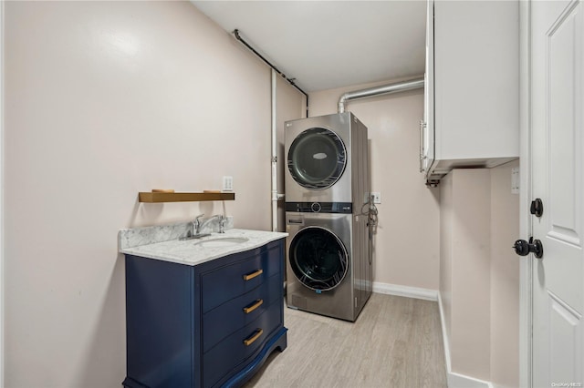 laundry area with cabinets, light hardwood / wood-style floors, stacked washer / dryer, and sink