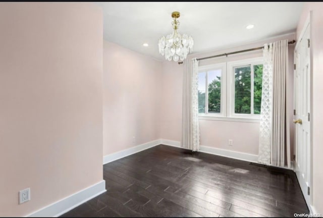 spare room featuring a chandelier and dark hardwood / wood-style floors